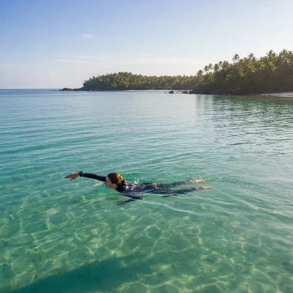 Open water swimmer with smartwatch tracking performance in a lake.